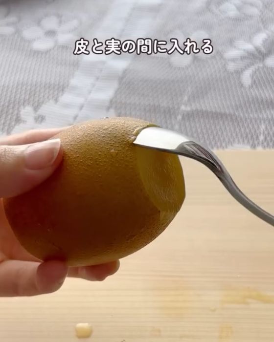 上下を切り落としたキウイの皮と実の間にスプーンを入れた様子