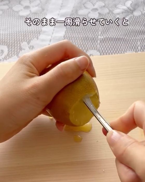 キウイの皮と実の間に入れたスプーンをそのまま１周させる様子