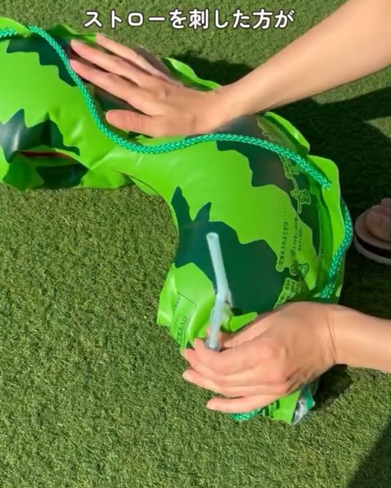 ストローを使って浮き輪の空気を抜く様子