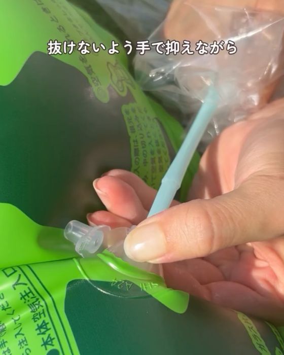 空気口に差し込んだストローを指で押さえる様子