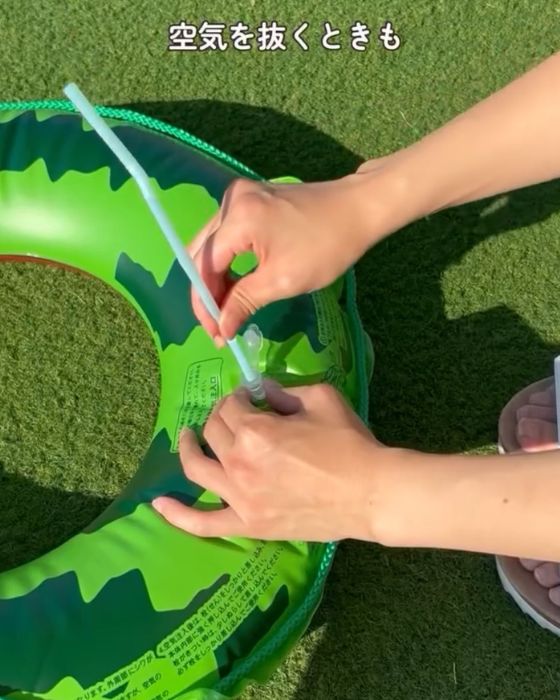 空気の入った浮き輪の空気口にストローを差し込む様子