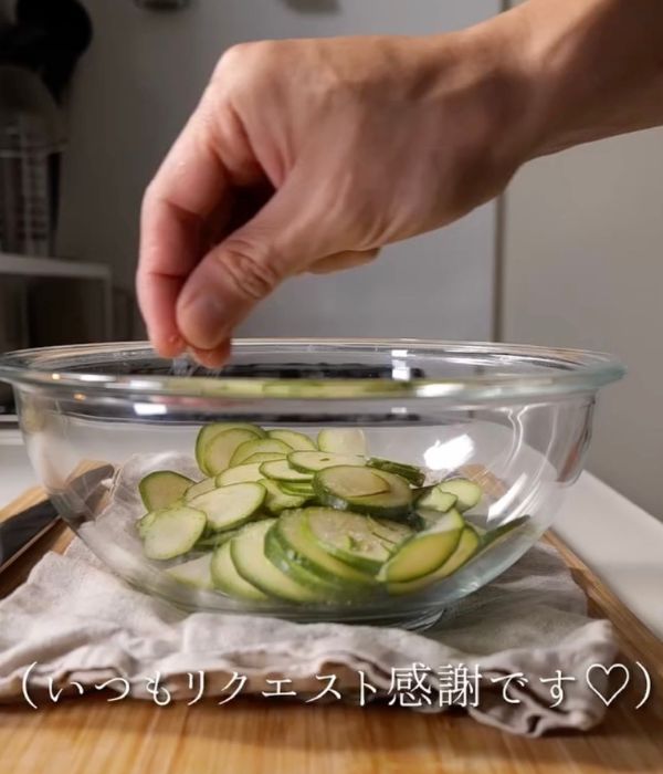 輪切りにしたズッキーニをボウルに入れて塩をかける様子