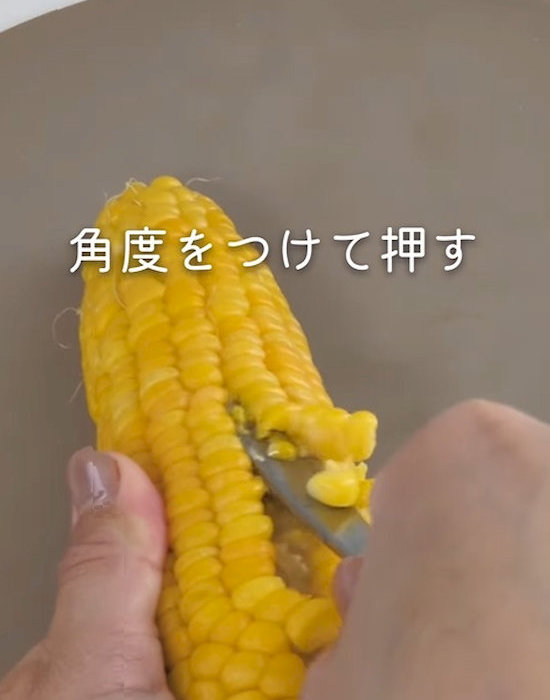スプーンでトウモロコシの粒を取り除いている様子