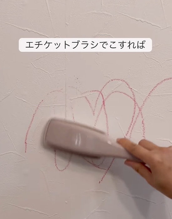 エチケットブラシで壁の汚れをこする様子