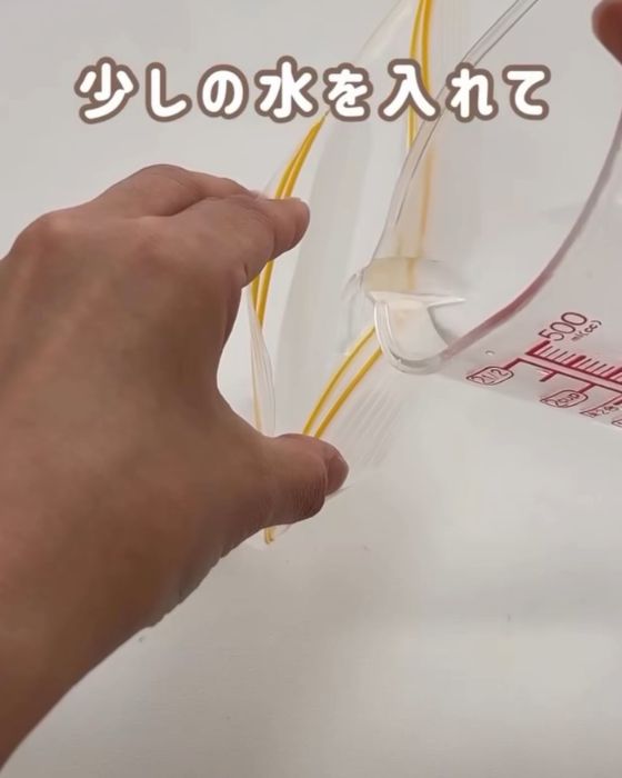 チャック付き保存袋に計量カップで水を入れる様子