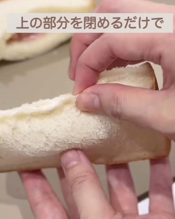 切り込み部分に具材を入れた食パンの上の部分を指でつまむ様子