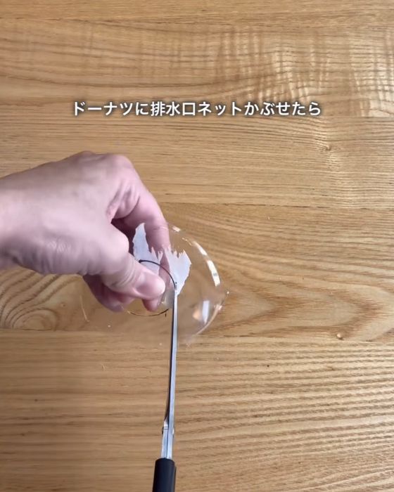 プラスチック容器の真ん中に書いた丸を線に沿ってハサミで切る様子