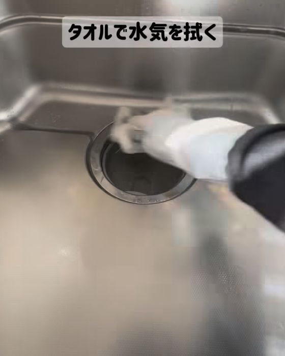 磨き終えたキッチンシンクの水気をタオルで拭き取る様子