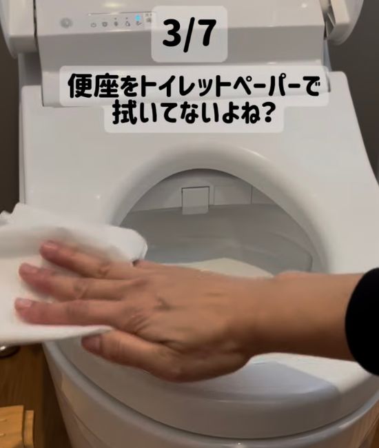 便座をトイレットペーパーで拭く様子