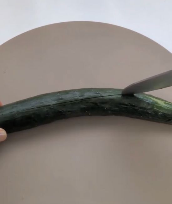 キュウリを裏返して包丁で縦に切り込みを入れる様子