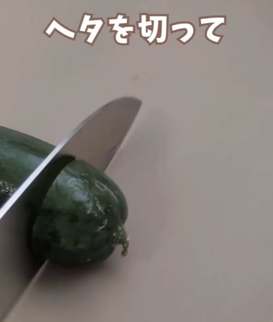 キュウリのツル側のヘタを包丁で切り落とす様子