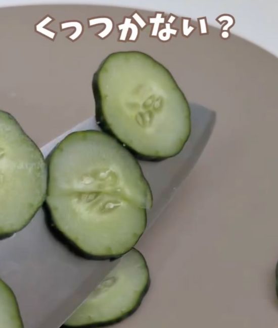 輪切りに切ったキュウリが包丁にくっついている様子
