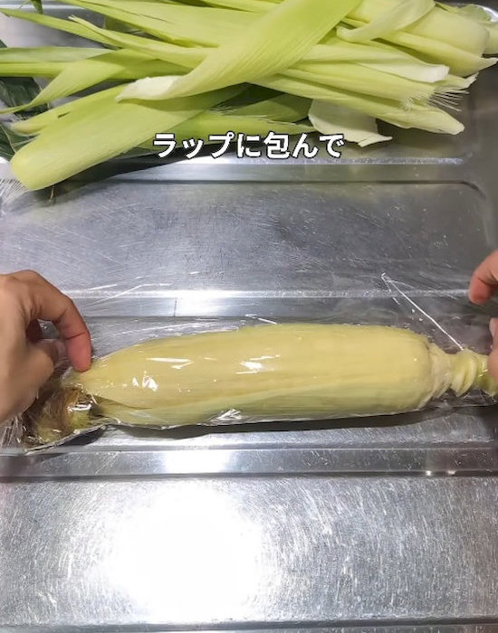薄皮の残ったトウモロコシをラップで包んでいる様子