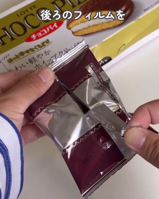 『チョコパイ』の個包装を裏返して中央のつなぎ目部分を下に引く様子