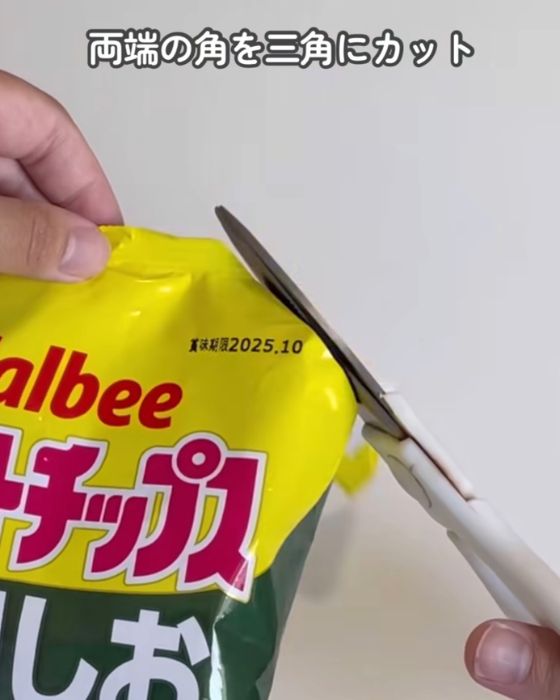 お菓子の袋の端をはさみで三角形に切る様子