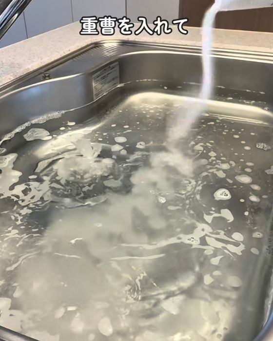 お湯をためたシンクに重曹を入れる様子