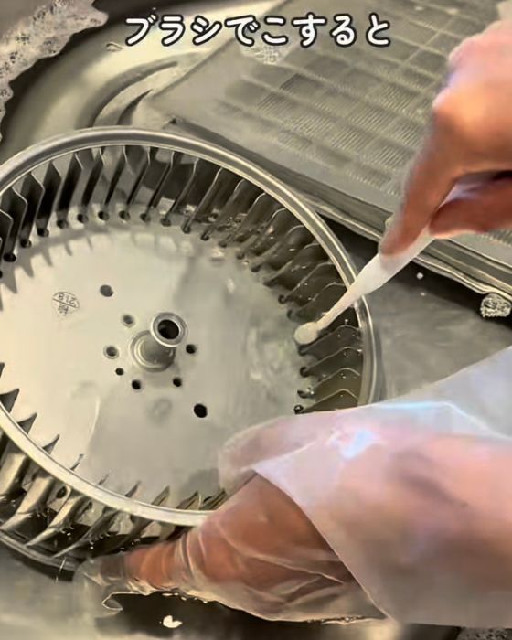 換気扇のパーツを歯ブラシで磨く様子