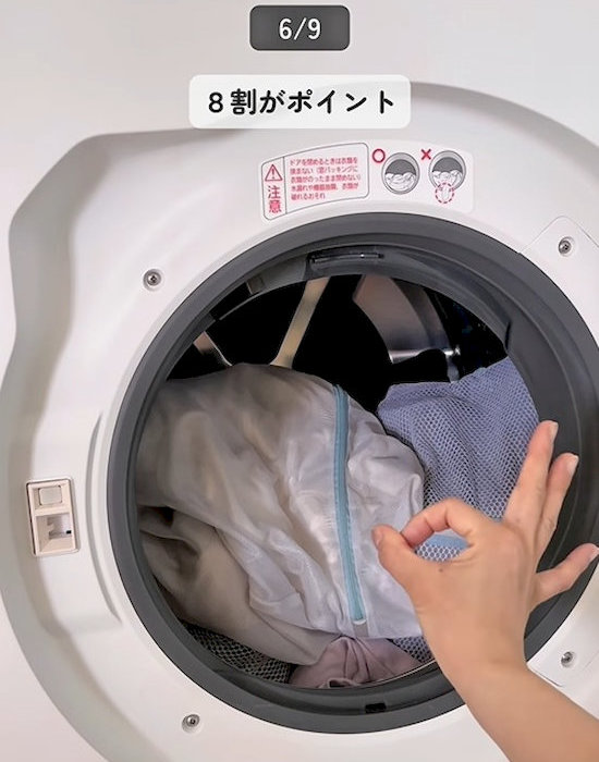洗濯機の前でOKポーズをする人