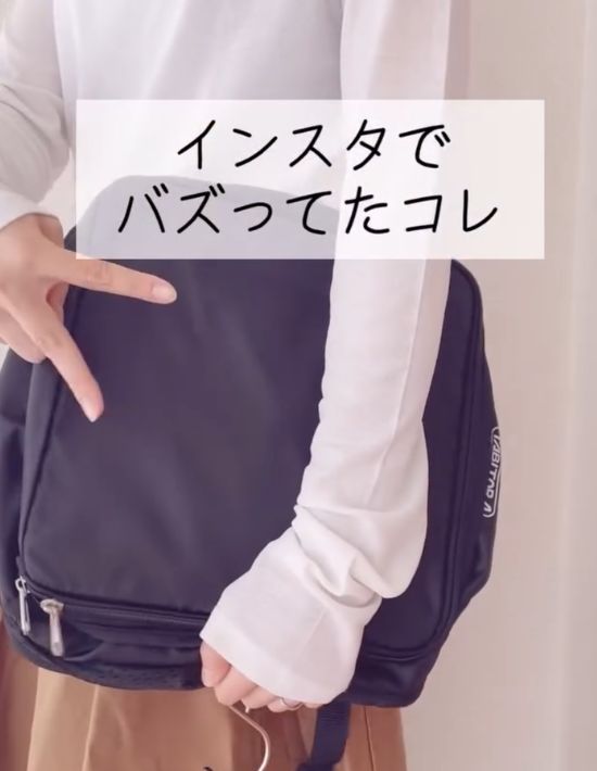 『TABITORA』の『クローゼット吊り下げ インナーバッグ』を腕に抱えてピースサインを向けている様子