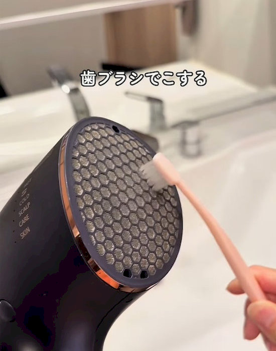 歯ブラシでドライヤーのフィルターを掃除している様子