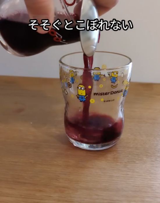 コップのふちにスプーンをあてて、飲み物を注いでいる様子