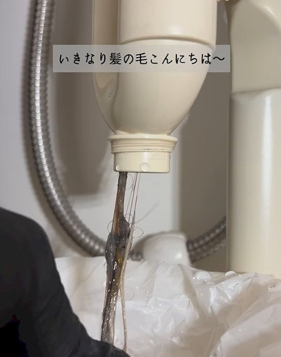 洗面台下の配管から髪の毛を取り除いている様子
