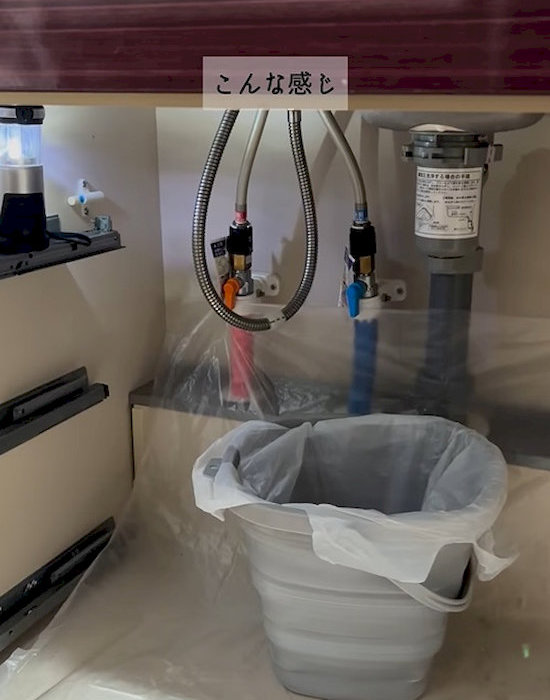 キッチンのシンク下にバケツを置いている様子