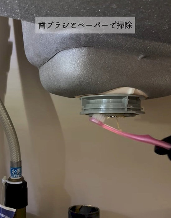 排水口を歯ブラシで掃除している様子