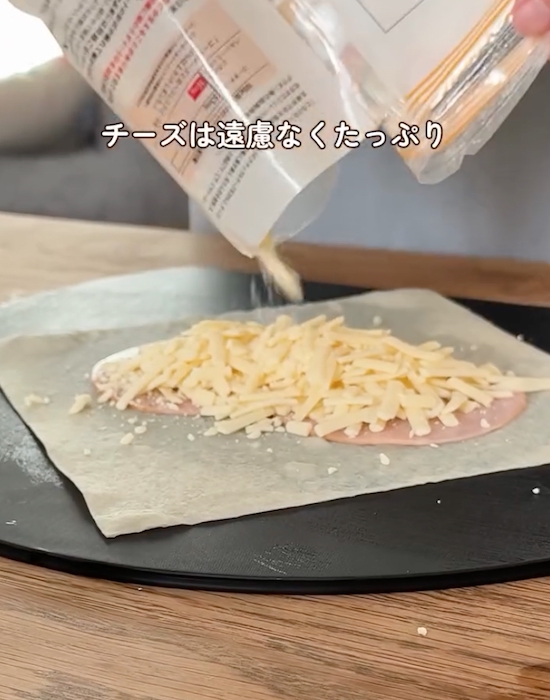 ハムの上にシュレッドチーズをかける様子