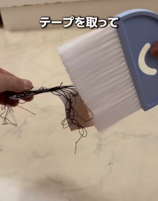 ほうきに付けたテープを剥がす様子