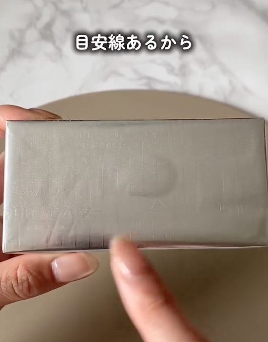 バターの銀紙に印刷された目安線を指差す様子