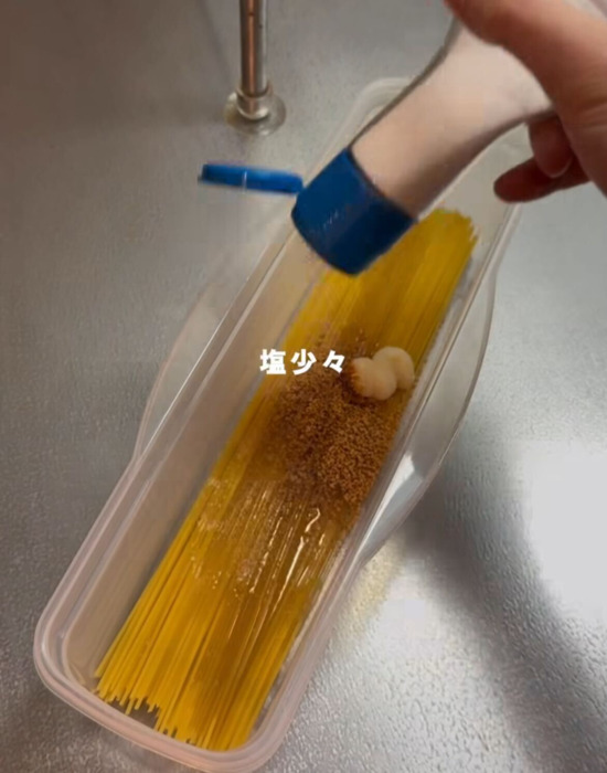 パスタに調味料を振る様子