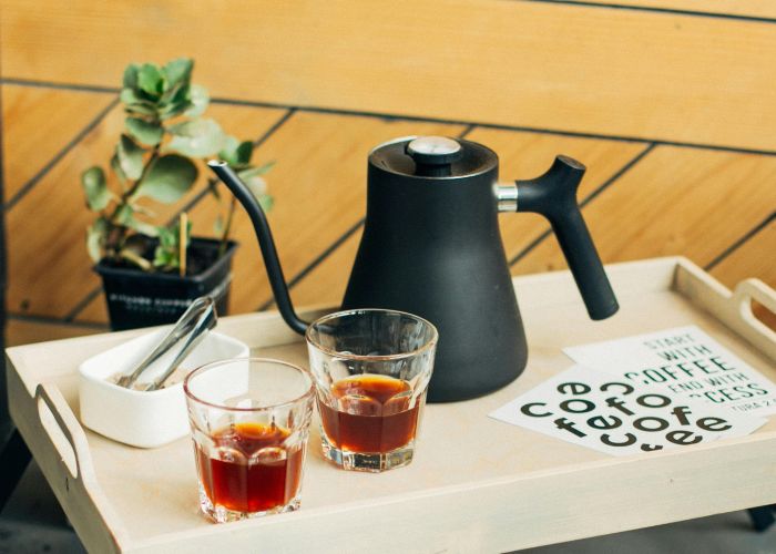 ミニーテーブルに置かれた飲み物の入ったグラスと電気ポットの写真