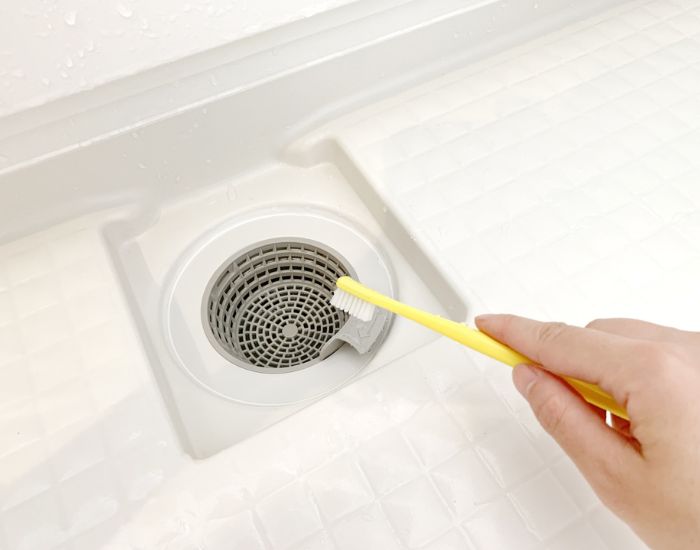 排水口に歯ブラシをあてようとしている様子