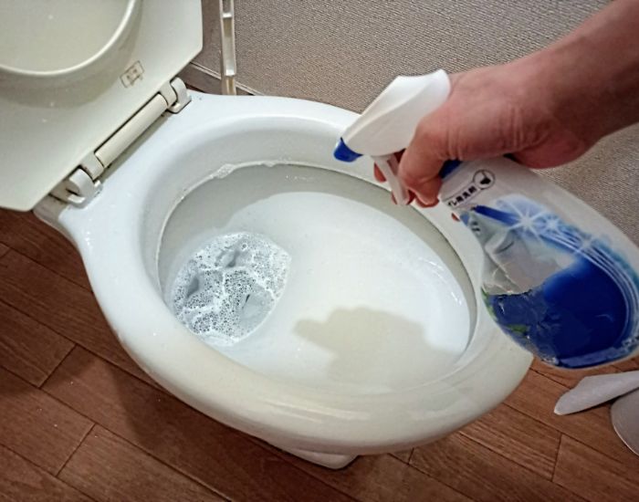 トイレの便器に掃除用洗剤を吹きかけている様子