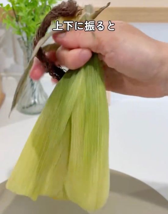 トウモロコシのヒゲのあたりを持って上下に振る様子