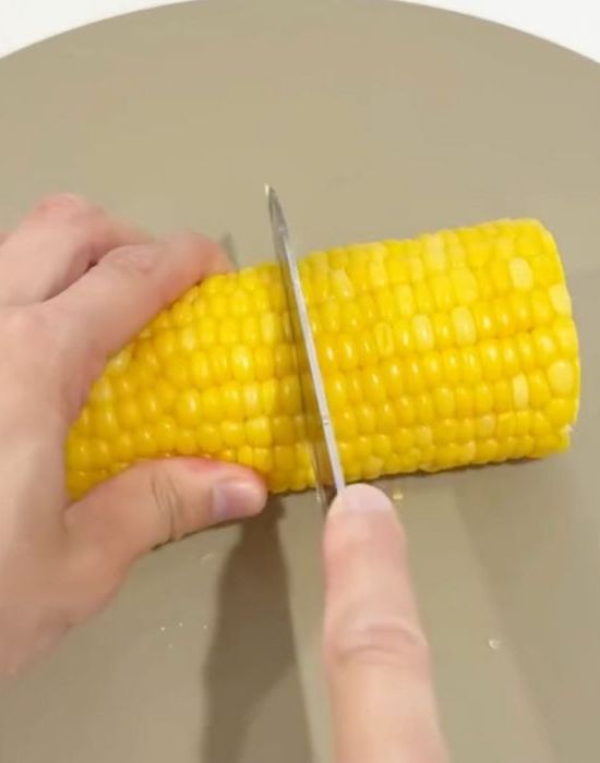 皮をむいたトウモロコシに包丁を入れた様子