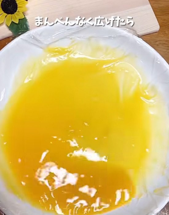ラップを敷いた耐熱皿に溶き卵を入れる様子