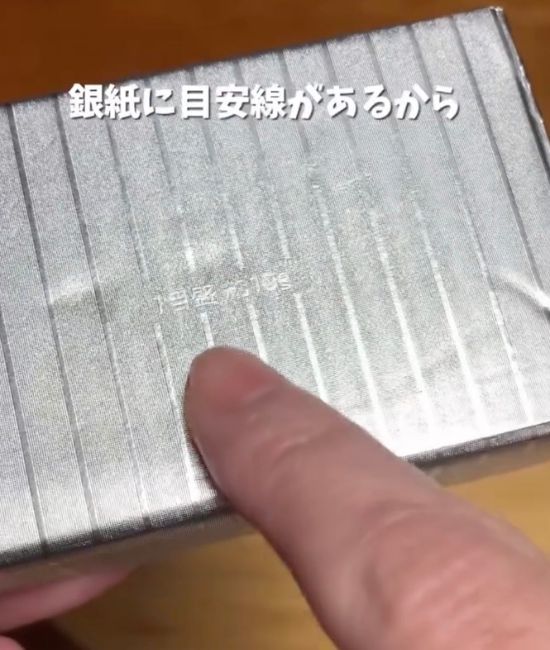 バターの銀紙に印刷された目盛り線を指さす様子