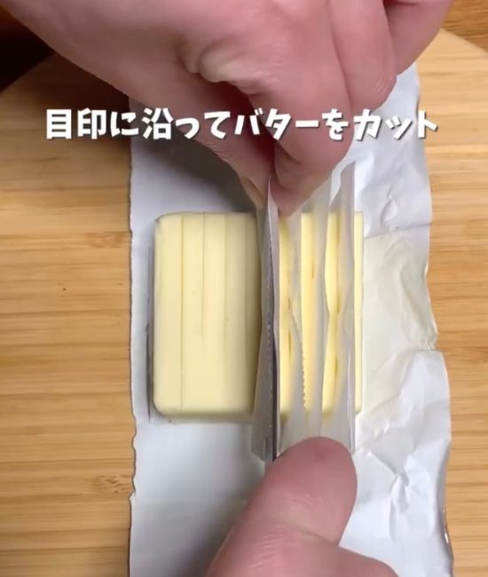 クッキングシートを巻いた包丁でバターを切り込みに合わせて切る様子