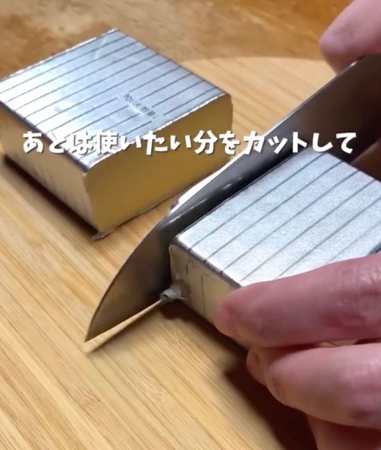 銀紙の上から包丁でバターを半分に切った様子