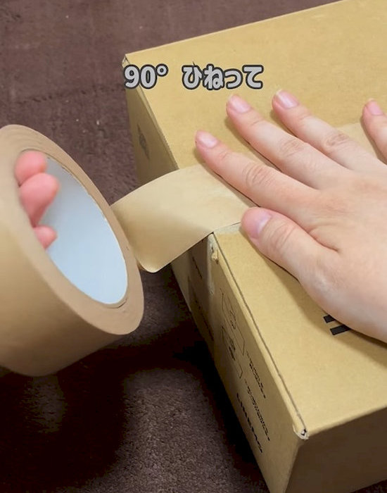 ダンボールに貼り付けたクラフトテープをひねっている様子