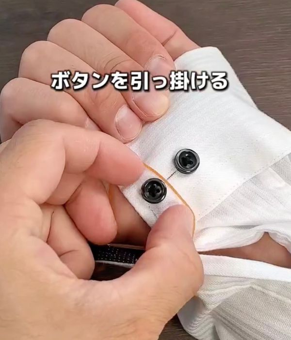 ボタンホールに通した輪ゴムをボタンに引っかける様子