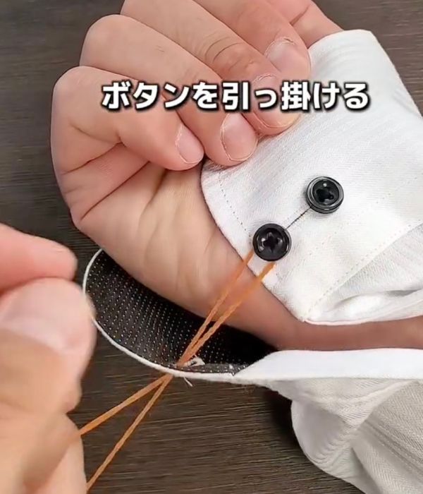 ボタンホールに通した輪ゴムのボタンをかけていないほうを引っ張る様子
