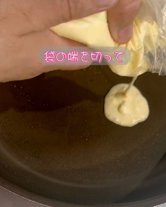 袋の角を切ってフライパンにホットケーキの生地を入れる様子