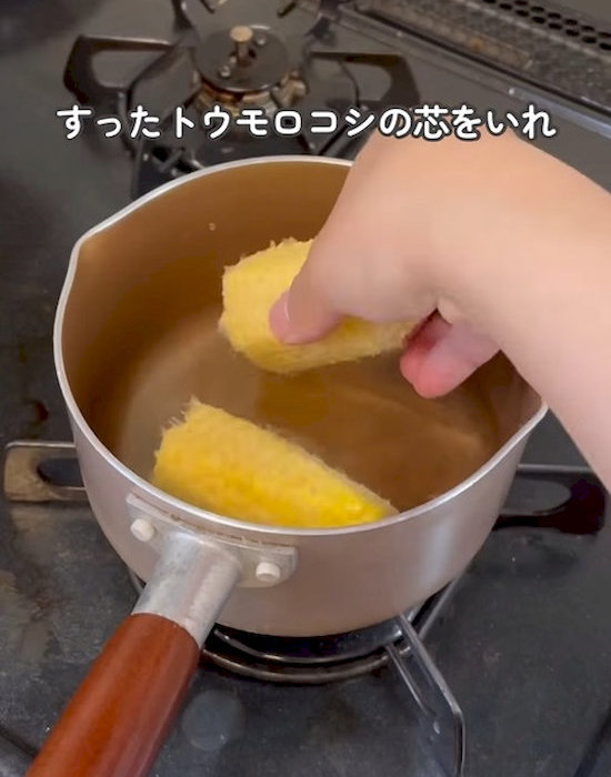 鍋にトウモロコシの芯を入れる様子