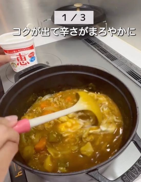 カレーにヨーグルトを入れてお玉で混ぜ合わせる様子