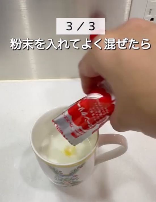 牛乳を入れたマグカップに粉末コーンスープを入れる様子