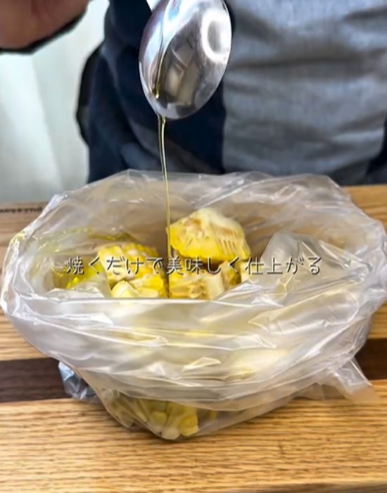 ポリ袋に入れたトウモロコシに調味料を入れる様子