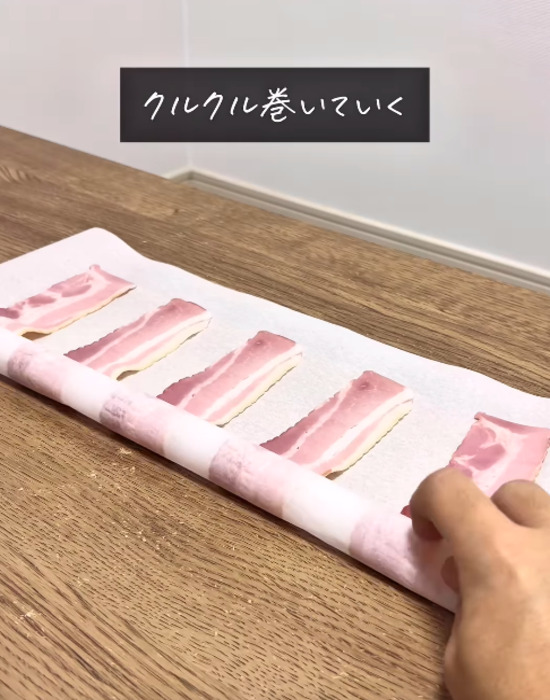 ベーコンをのせたクッキングシートを巻く様子